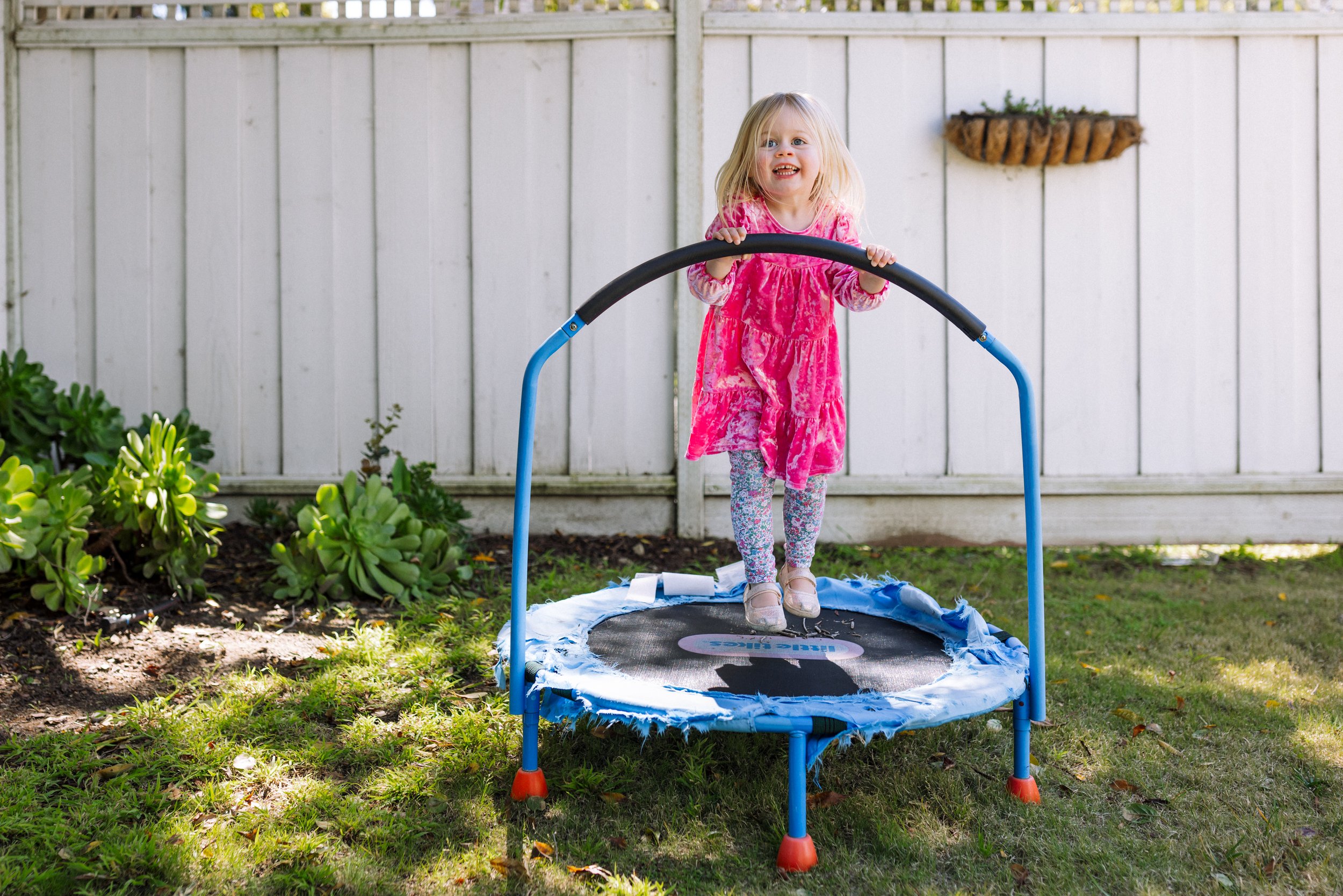 toddler girl jumping on small trampoline by herself and smiling