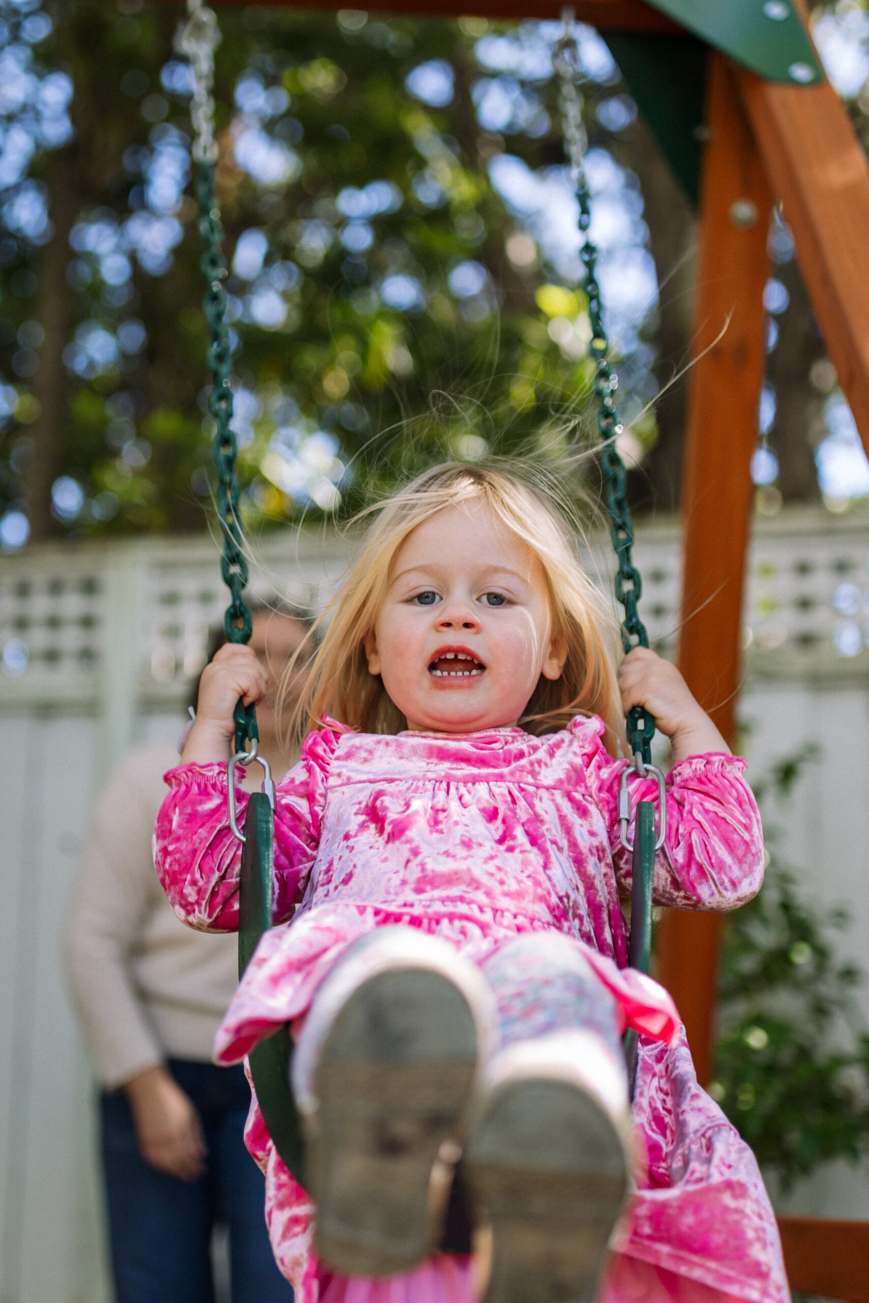 toddler girl being pushed by mom on swing in the backyard