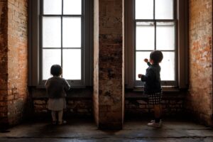 brother and sister standing in front of windows at Fort Point during San Francisco Family session