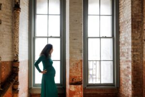 pregnant woman standing in front of windows at Fort Point during San Francisco maternity session