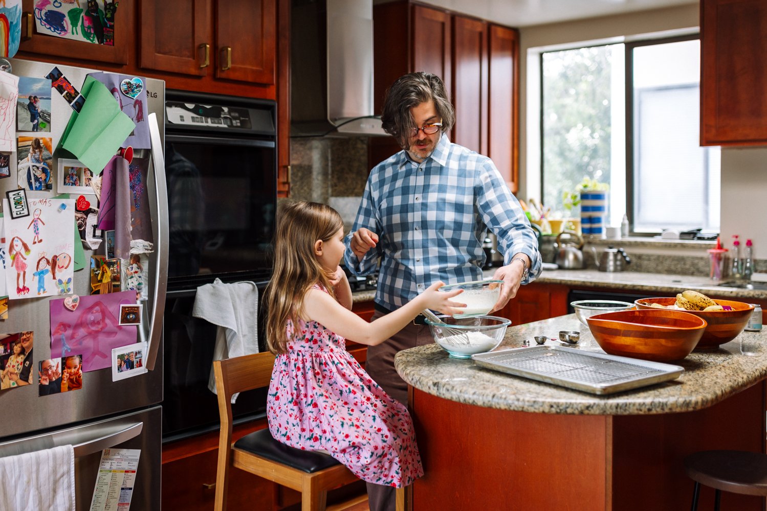 dad and daughter standing at the island in the kitchen making pancakes together