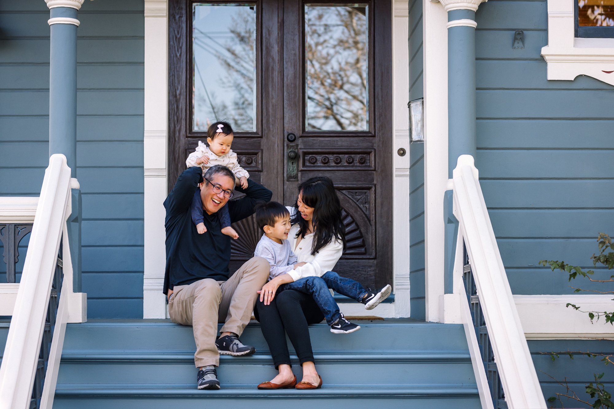 family of four sitting on the front porch together laughing and having fun