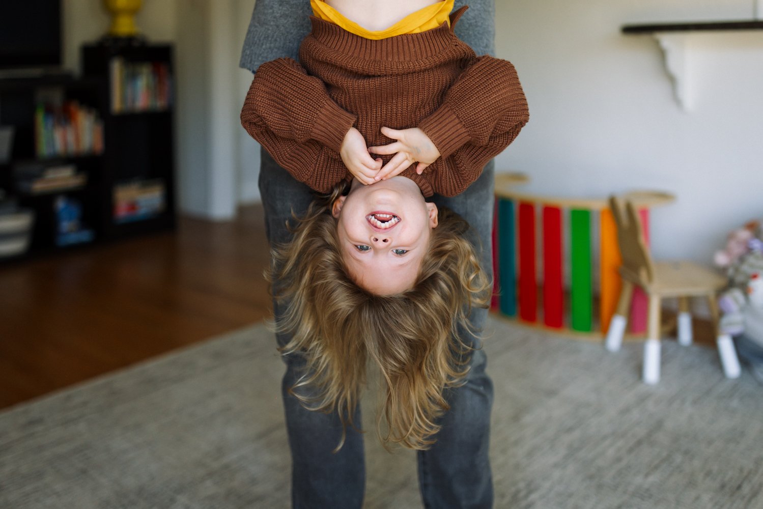 girl being held upside down and smiling while dad holds her