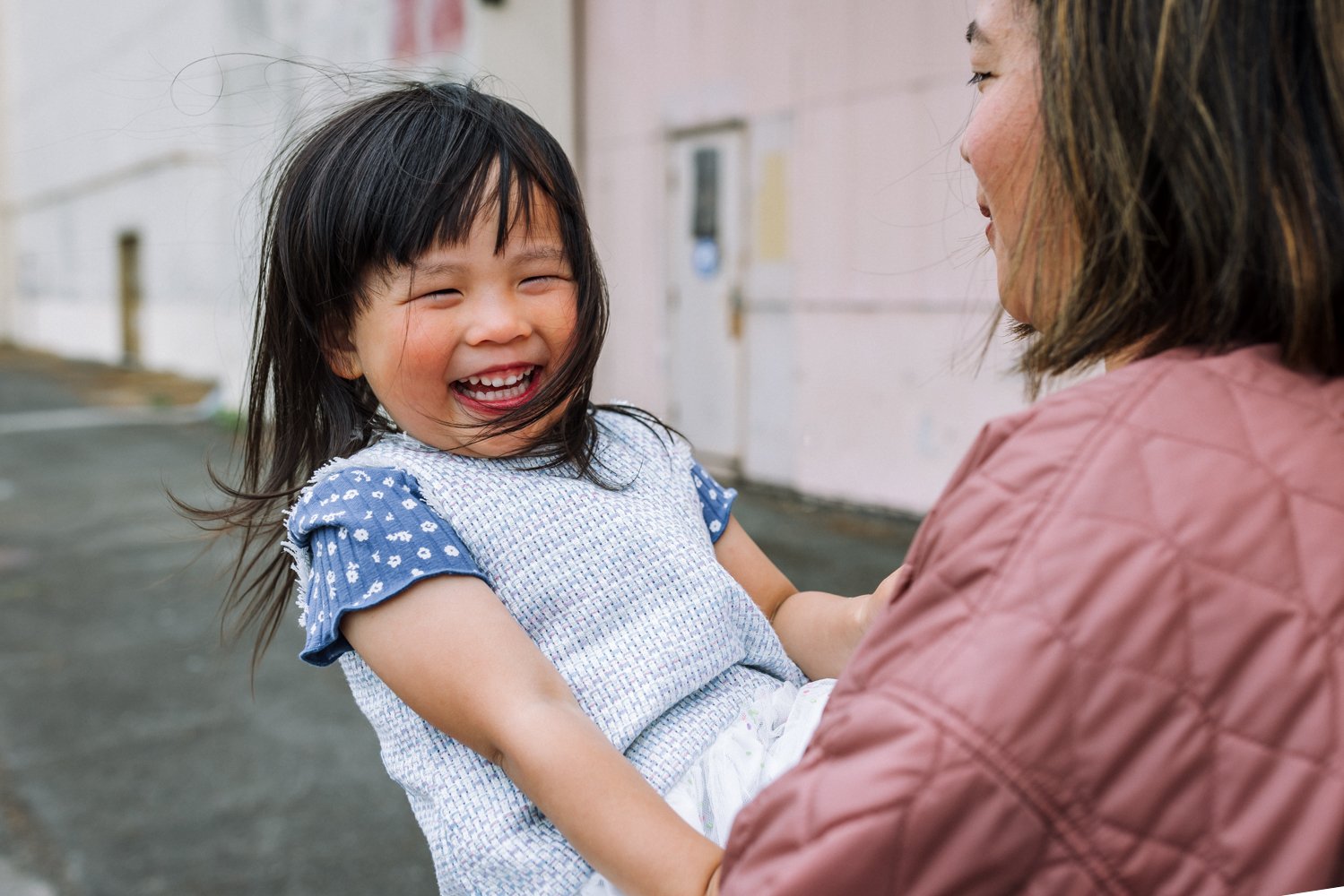 girl laughing as her mom holds her in her arms spinning her around