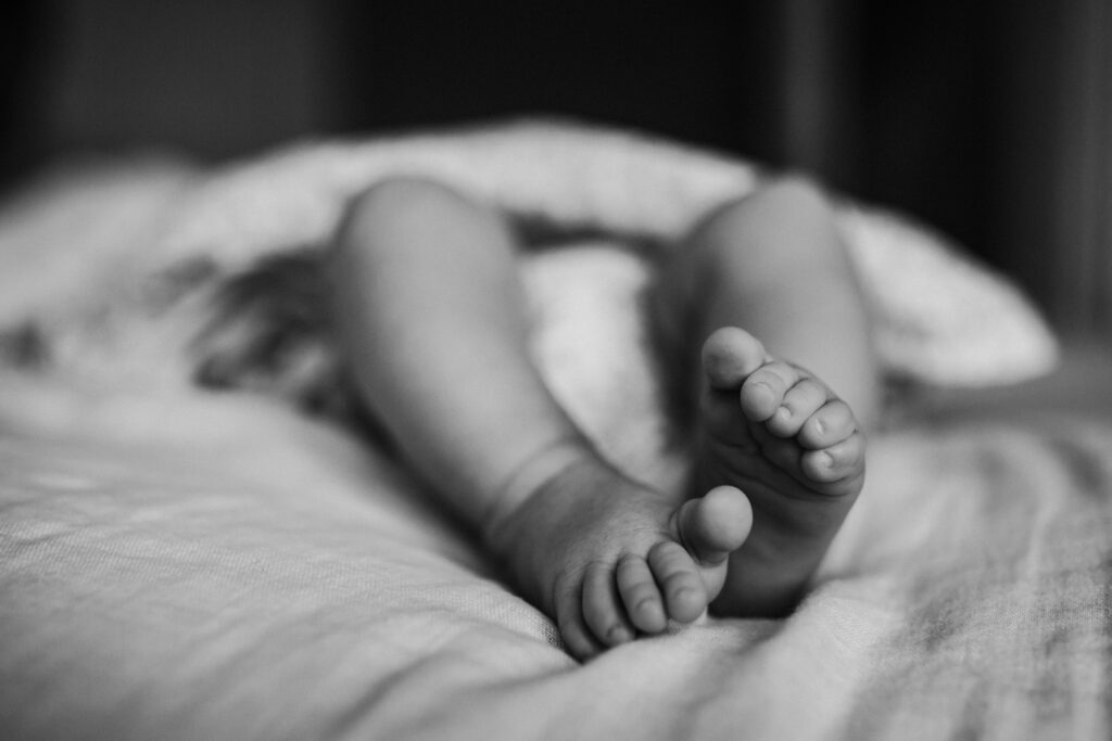 newborn legs and feet on mom and dad's bed