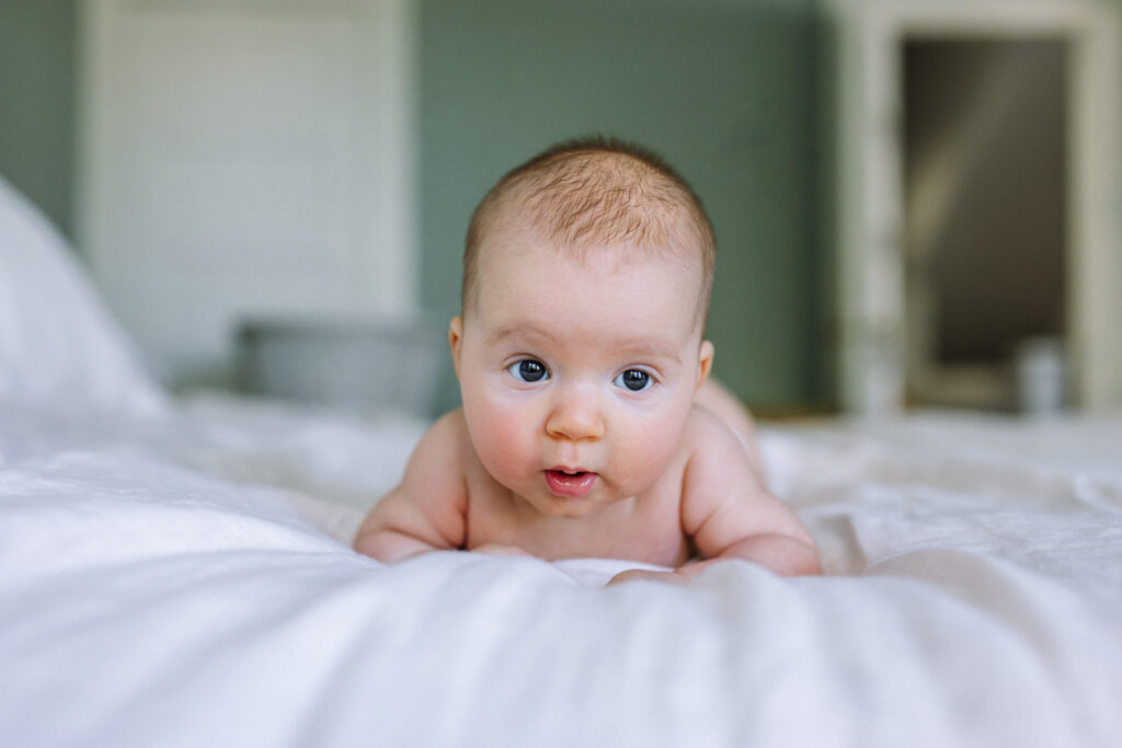 newborn in diaper on her tummy propping herself up with her arms and eyes wide open