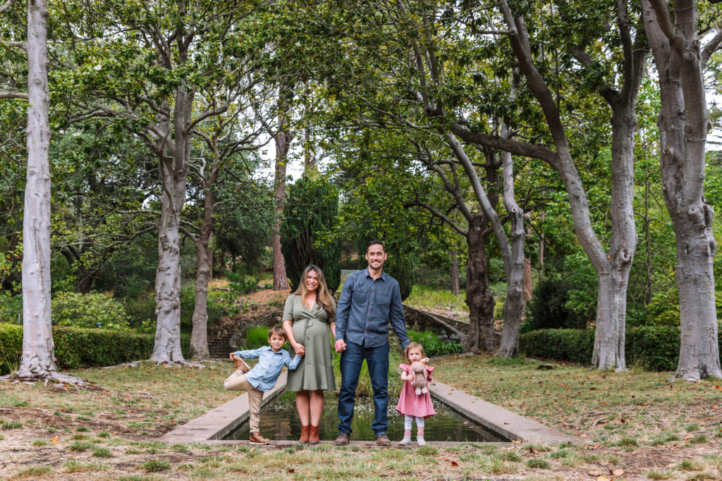 Family with two young children posing among tall trees in the East Bay