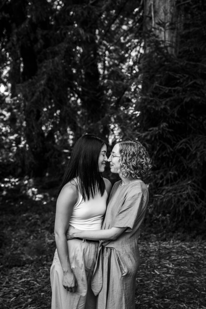 Two women smiling and touching foreheads in a forest setting