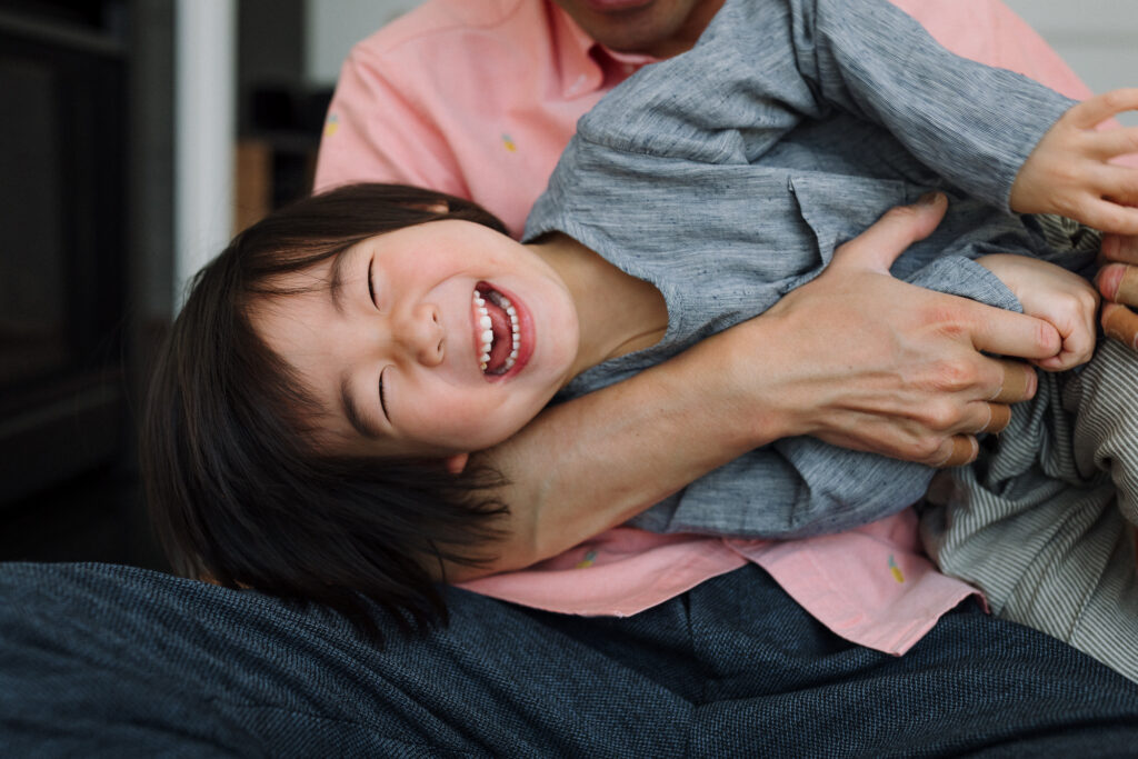 boy laughing in dad's arms while being tickled