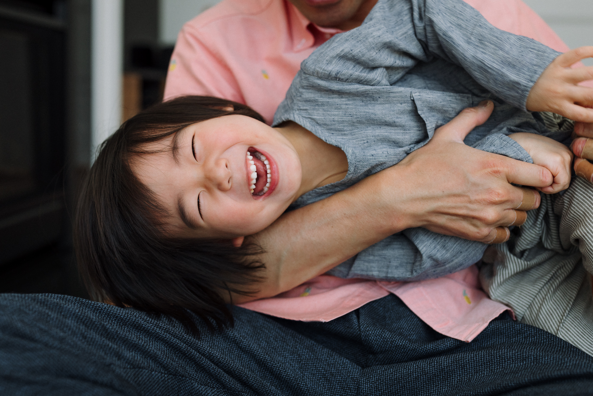 boy laughing in dad's arms while being tickled
