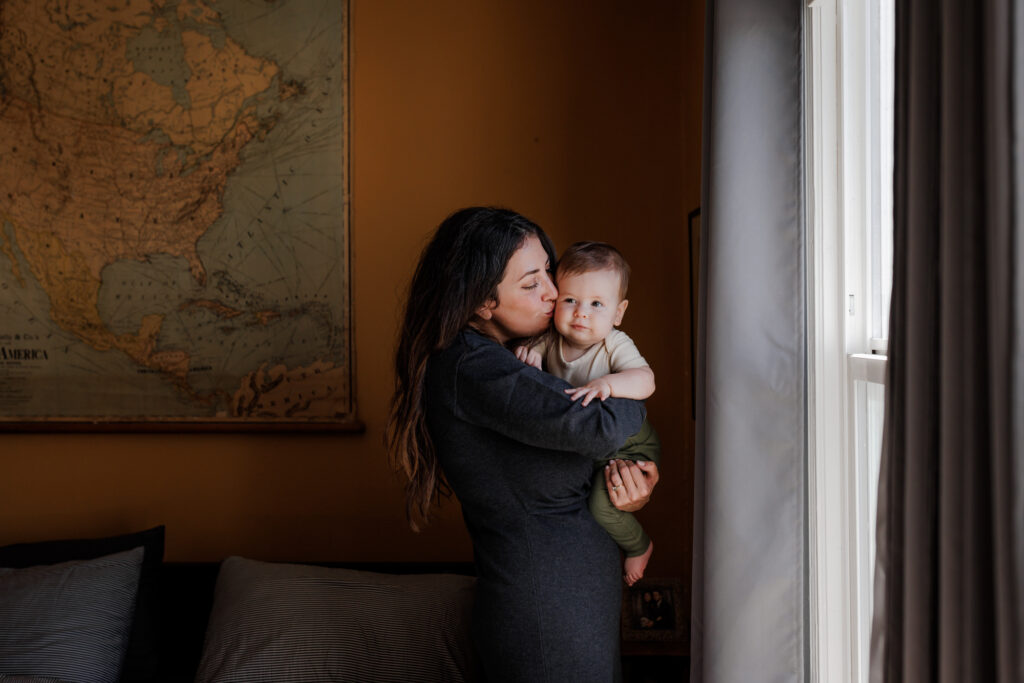 Mother holding baby by the window in a cozy bedroom