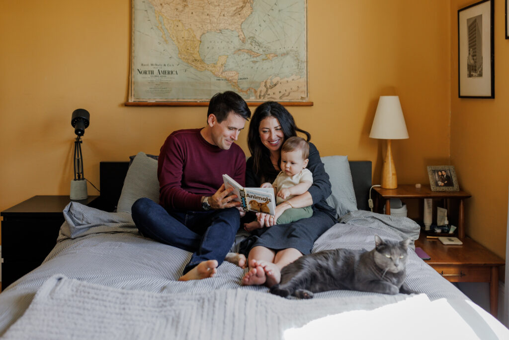 Family reading together on a bed with their cat nearby