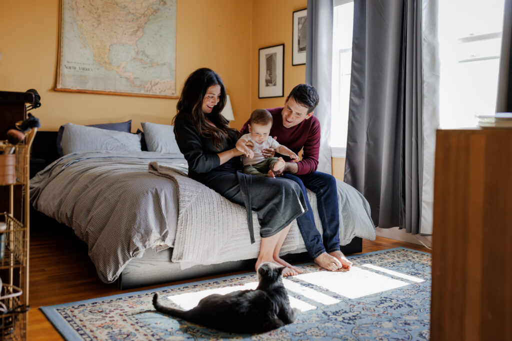 Parents cuddling baby on the bed with natural light streaming in