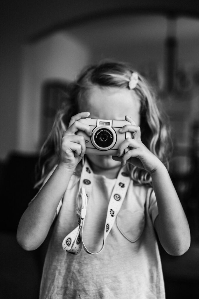 little girl holding camera and taking a photo