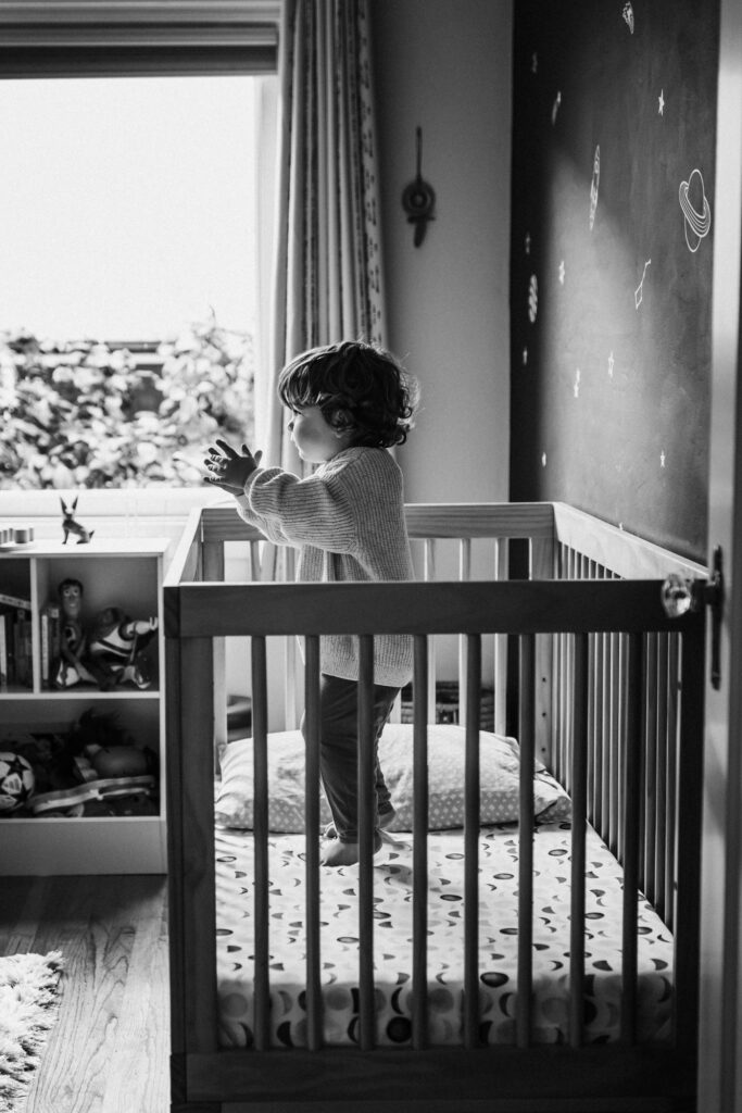 Toddler standing in crib and clapping hands