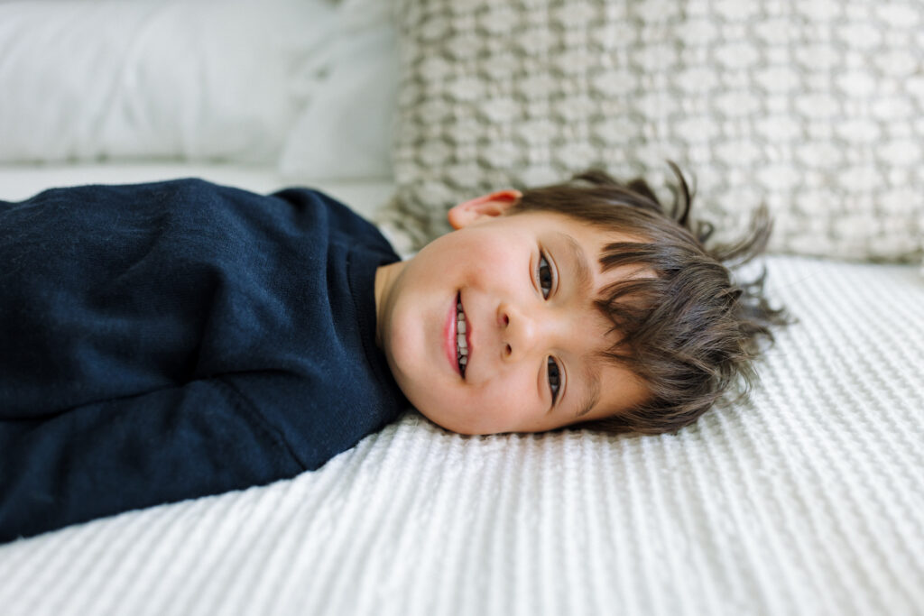 toddler lying face to face with newborn sibling smiling Alameda newborn photographer