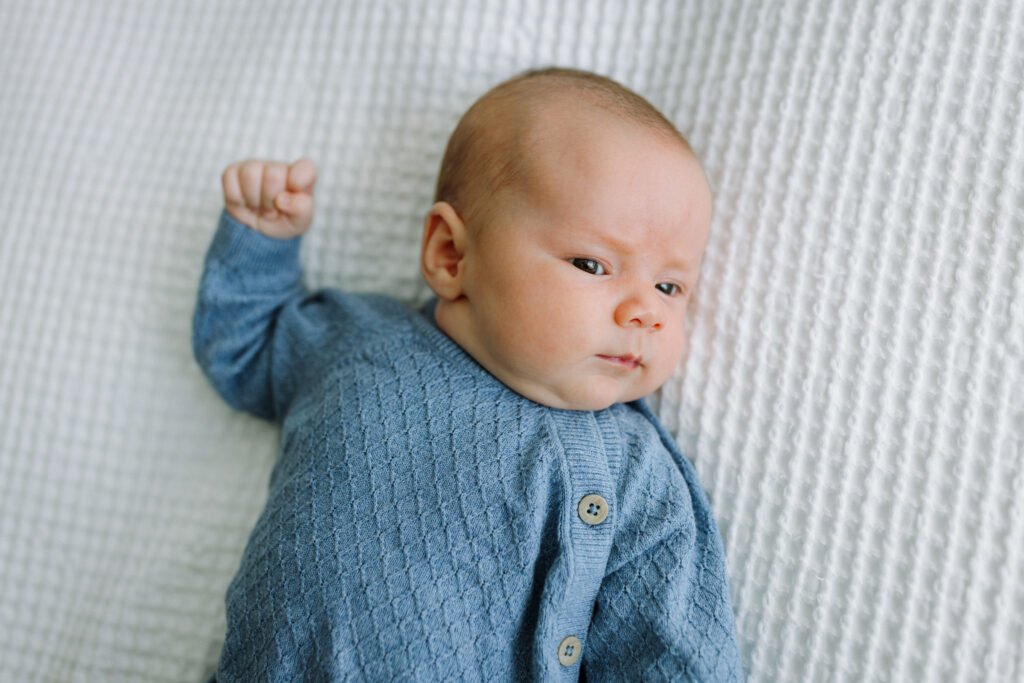 alert newborn with fist raised during in-home newborn session Alameda