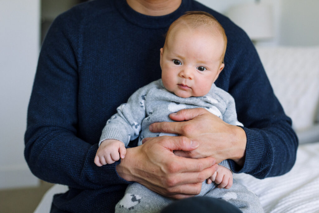dad holding alert newborn against his chest at home Alameda newborn photographer