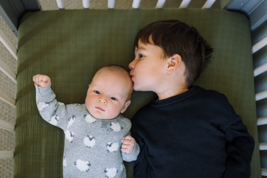 brother kissing newborn sibling in crib East Bay newborn photography