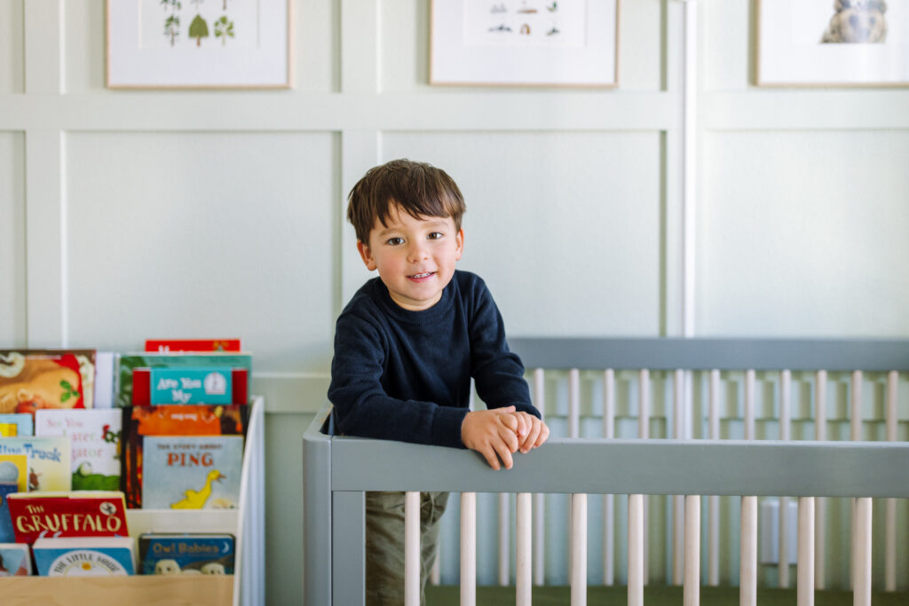 toddler standing at baby's crib during in-home newborn session Alameda