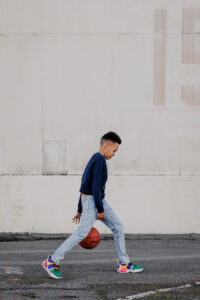 portrait of a boy dribbling basketball through his legs at East Bay hangar