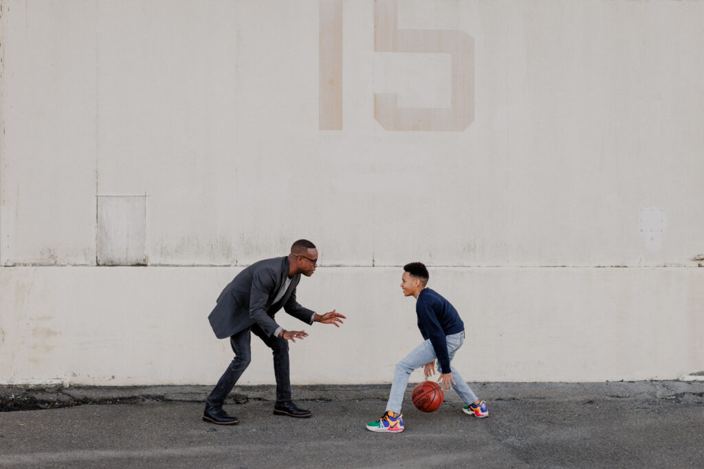 father and son playing basketball at hangar in Alameda