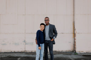 Father and son standing in front of a pink hangar at the Alameda Naval Base