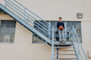 Boy holding a basketball on a metal staircase at an industrial location during a family session