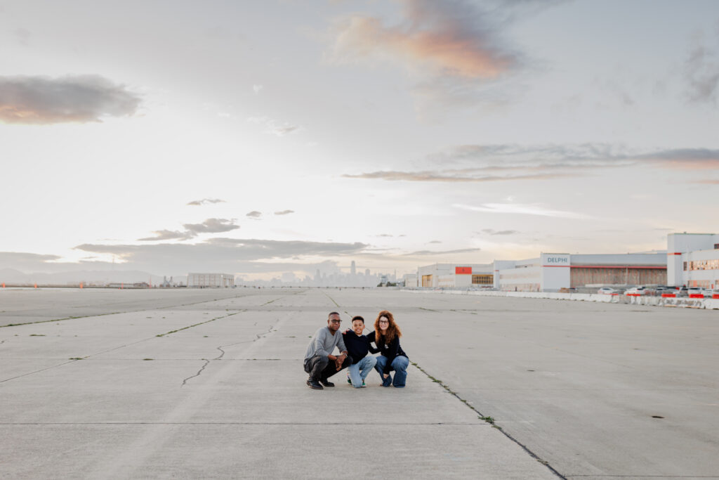 Family sitting together on the open tarmac during an East Bay family session