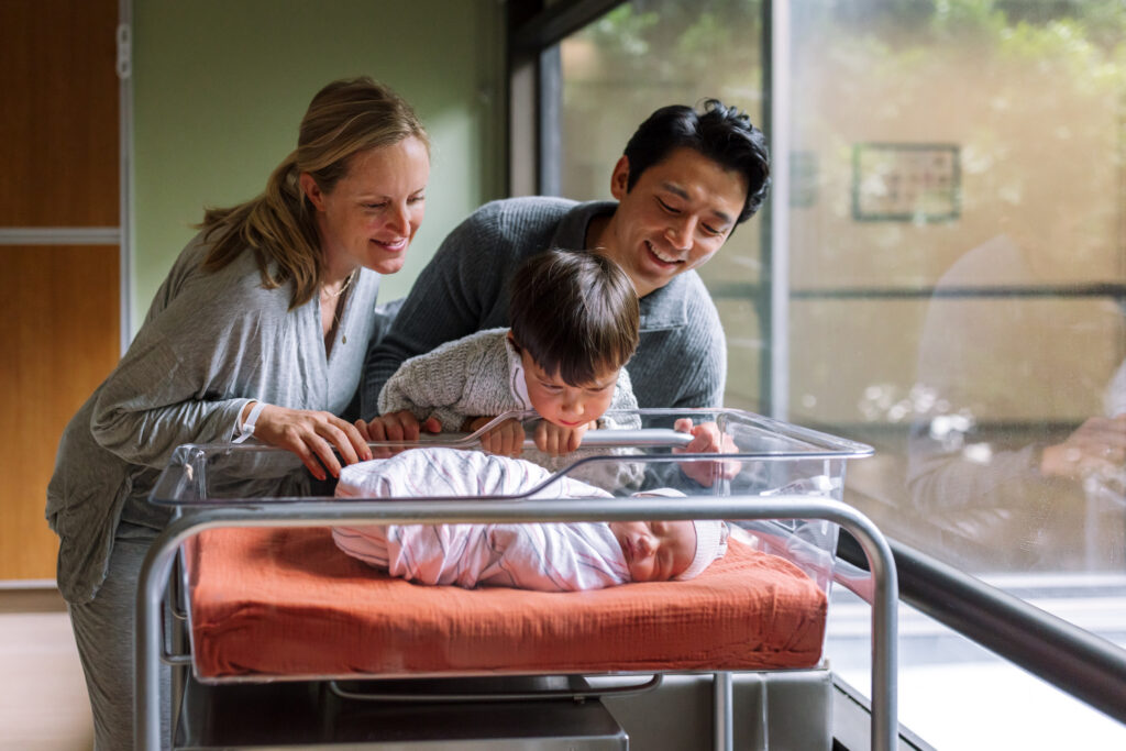 parents looking at newborn in hospital bassinet during Fresh 48 session Alta Bates