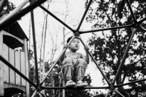 boy climbing on backyard play structure during family session in the East Bay