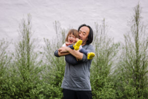 Dad laughing while holding his toddler daughter outdoors during a Bay Area family photography session