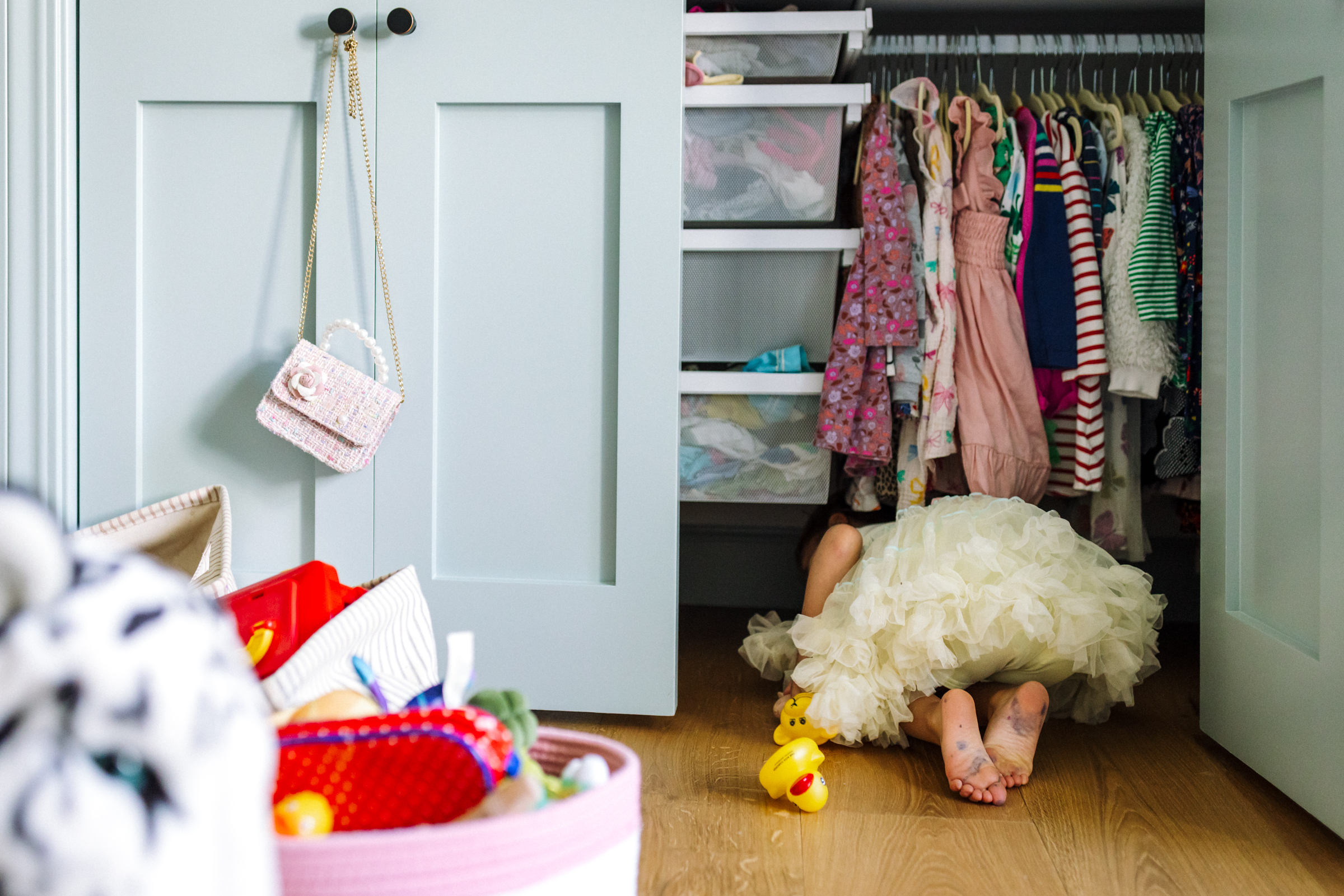Girl in white tutu hiding in closet during an in-home family photography session in Oakland