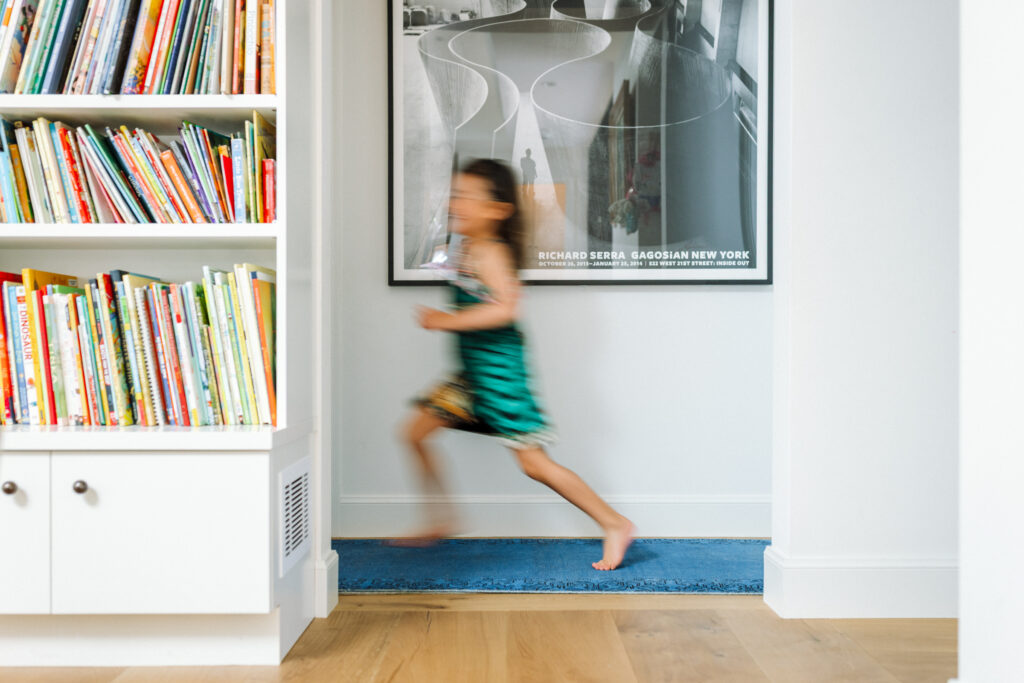 Young girl running through her home during an in-home family photography session in Oakland
