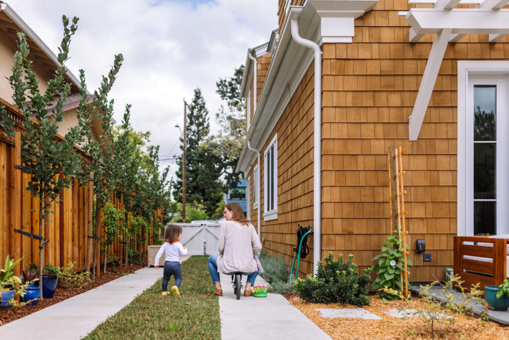 Mom following her toddler down a garden path during a relaxed outdoor family session in Oakland