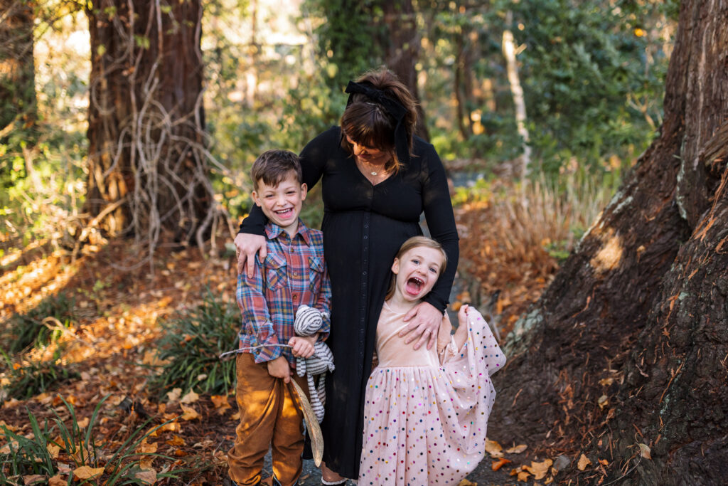 A pregnant woman laughs with her two young children on a garden path surrounded by fall color at the UC Botanical Garden in Berkeley