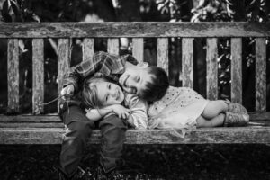 Two siblings lie together on a wooden garden bench laughing at the UC Botanical Garden in Berkeley
