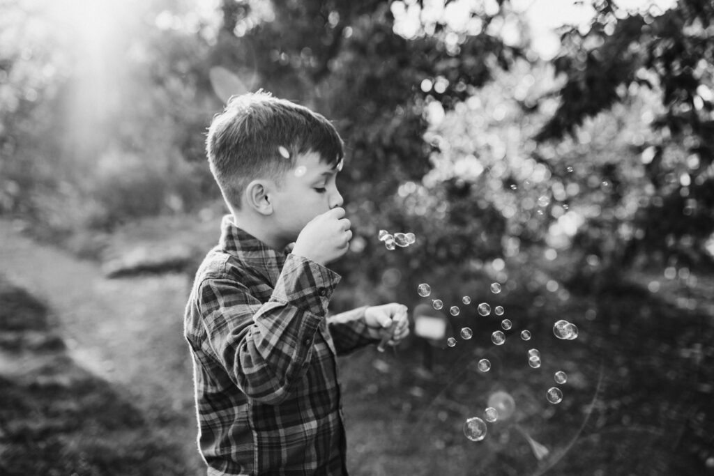 A boy blows bubbles in a garden at the UC Botanical Garden in Berkeley during a family session