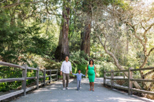 A pregnant woman, her partner, and young son walk hand in hand along a paved path at the UC Botanical Garden in Berkeley
